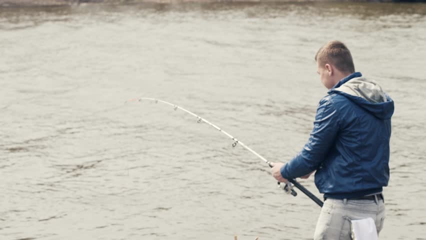 Fisherman catching fish. Angler taking caught fish from hook on fishing rod