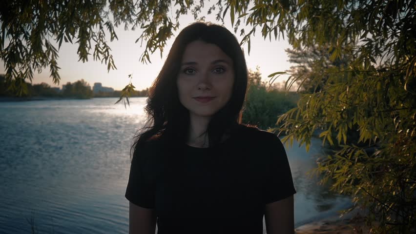 portrait of young pretty brunette woman on a sunset background on a lake