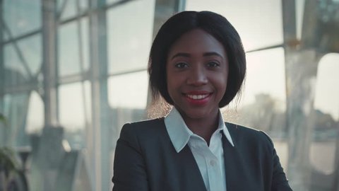 Gorgeous beautiful Afro-American woman in a stylish suit cutely smiling straight to camera.