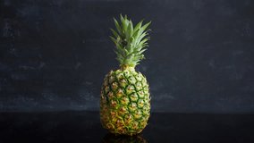 Stop motion ripe tropical fruit pineapple on a black background. Time lapse food loop footage