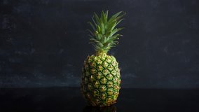 Stop motion ripe tropical fruit pineapple on a black background. Time lapse 