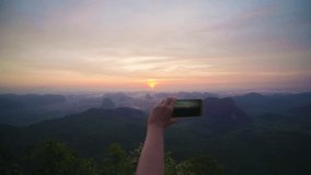 Women's hands taking video of the landscape with a beautiful sunset on a smartphone. POV 4K