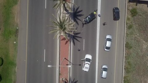 Car crash on a highway - Police car blocking the left lanes, to protect a black car with severe impact to the front, while diverted traffic passing slowly to the right. Top down aerial footage.