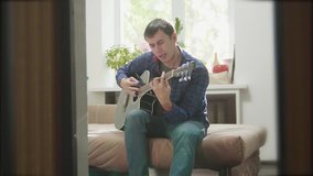 man playing music by wooden acoustic guitar. Man Playing Acoustic Guitar Close Up slow motion video. in the room lifestyle sits on the couch. man and guitar concept