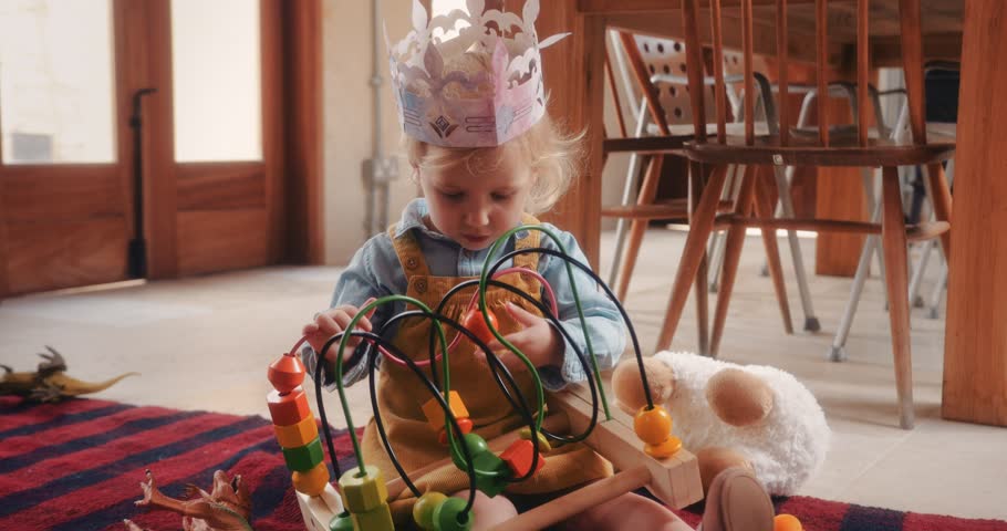 Girl having fun sitting on carpet and playing with educational wooden toy on the floor