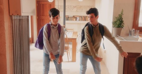 Happy young brothers returning from school and dancing the viral floss dance together at home