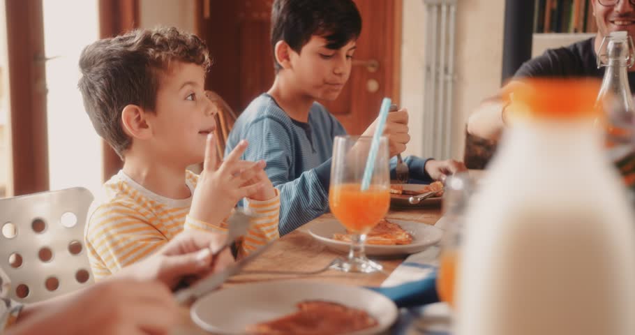 Happy family with sons having fun sitting around kitchen table and eating breakfast together Royalty-Free Stock Footage #1012743569