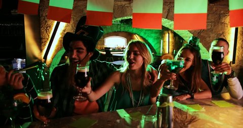 Young multi-ethnic friends drinking beer and green cocktails at Saint Patrick's day Irish pub party