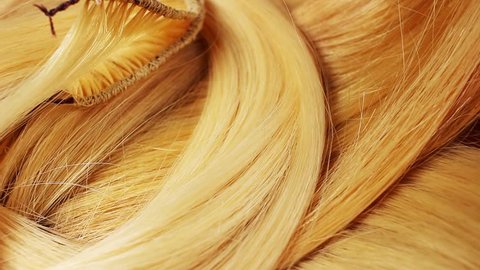 Hair extension cutted hair fibers blonde weft rotating pattern macro texture background backdrop footage video.