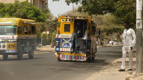 Senegal, Africa, June 2018. Street with colorful buses passing in city of Dakar.
