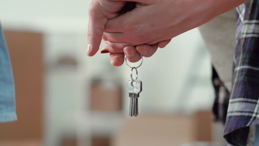 Close-up - the hands of an unidentified young couple holding the keys to a new apartment. Happy newlyweds go to a new apartment | Shutterstock HD Video #1012750391