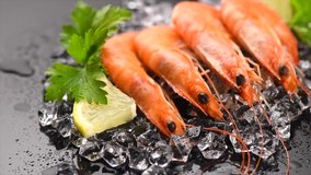 Shrimps. Fresh Prawns on a Black Background. Seafood on crashed ice with herbs, dark background, Served food, preparing healthy food, cooking, diet, nutrition concept. Slow motion 4K UHD video