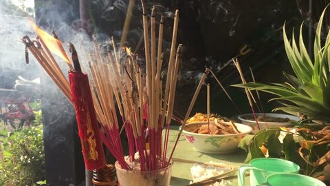 Food offerings on chinese new year festival for pray of god, or ancestor worship, has smoke from incense and candle, with daybreak light, Bangkok, Thailand, 2018.
