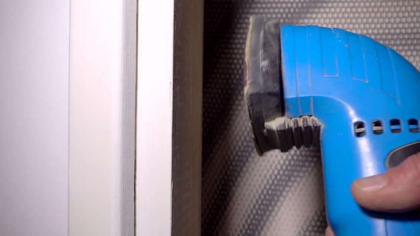 Closeup slow motion shot of a small power sander being used to sand the paintwork on interior woodwork.