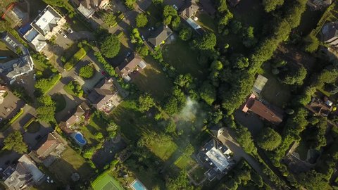 Aerial drone flight over a small farming community in rural England on a bright sunny day.  Fields and trees are bright green in the summer light.
