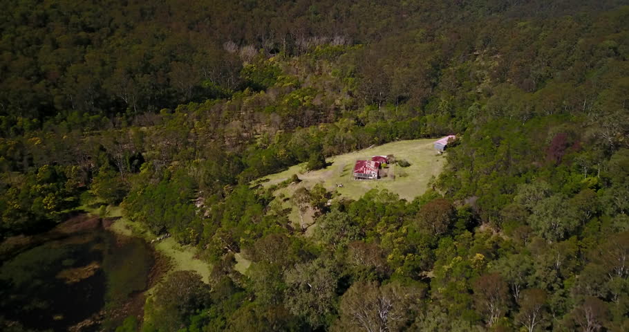 Drone UAV flies through valley over a spooky old house in the middle of nowhere.