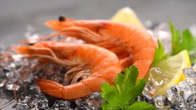 Shrimps. Fresh Prawns on a Black Background. Seafood on crashed ice with herbs, dark background, Served food, preparing healthy food, cooking, diet, nutrition concept. Slow motion 4K UHD video