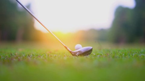 Slow motion golf sport concept, golfer hitting golf ball to hole for winner in golf course is beautiful fairway on sunset. Close up shot tee off on green grass for player playing in summer for relax