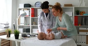 mother with child and young doctor examining on table in office.