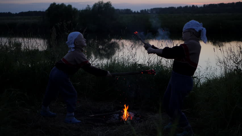 sparks from burning sticks. Battle of children to burning dubankah. children fight against the background of the river. Coals from burning sticks scatter in different directions. Slow motion