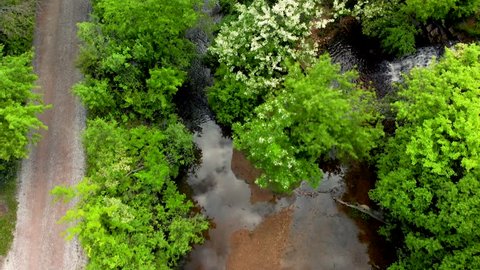 drone footage flying over green trees and a waterfall with canal water from the Illinois and Michigan canal flowing past two trails.