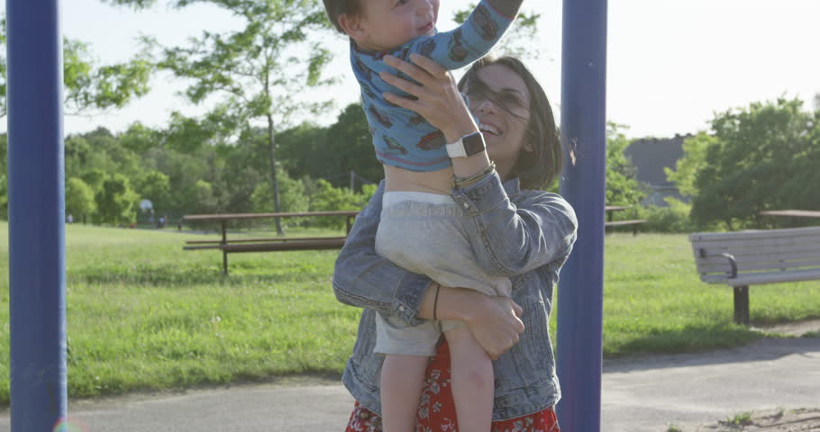 Toddler boy and mother playing at park during sunset - slow motion
