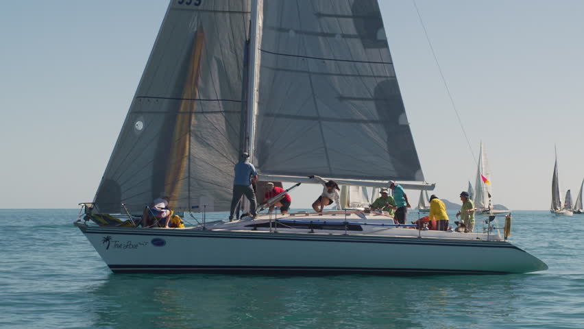 A wide slow motion shot of a man fixing the mast of the sailboat.