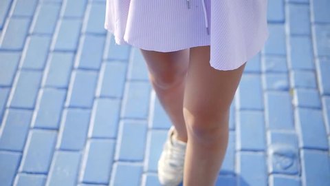 Close up shot of woman's lovely long legs in sneakers.