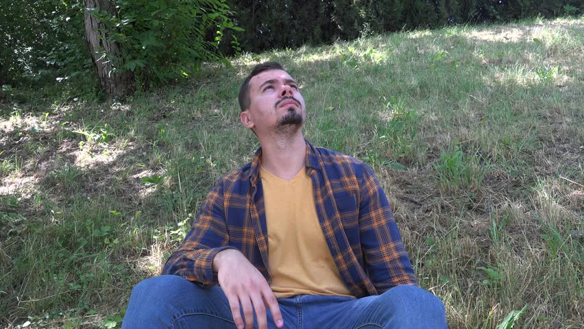 Sitting in green park worries difficulties lonely upset confused man looking sky