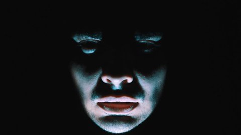 Nightmare shot of a demon face in the darkness moving around screaming and being scary while a light flashes on his face to add drama to the scene