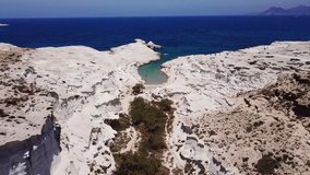 Aerial drone bird's eye view video of iconic lunar volcanic white chalk beach and caves of Sarakiniko, Milos island, Cyclades, Greece