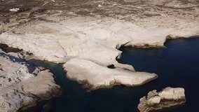 Aerial drone bird's eye view video of iconic lunar volcanic white chalk beach and caves of Sarakiniko, Milos island, Cyclades, Greece
