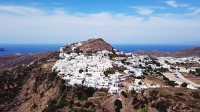 Aerial drone bird's eye view video of picturesque peak in chora and castle of Milos island overlooking endless blue of the Aegean sea, Cyclades, Greece