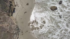 Aerial video facing down on southern California cost in Malibu at El Matador with  people under a clear sky in the morning 
