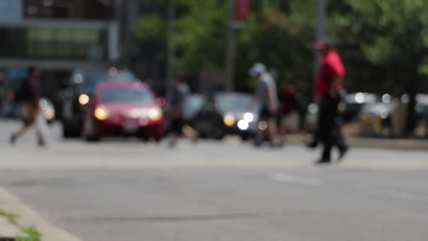 People crossing the street during the day time in soft focus. Blurry dreamy image of city traffic and people walking. Abstract view of movement. 