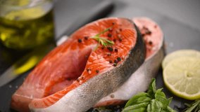 Salmon. Raw Trout Red Fish Steak with Herbs and Lemon and olive oil rotated on slate. Cooking Salmon, sea food. Healthy eating concept. Slow motion 4K UHD video
