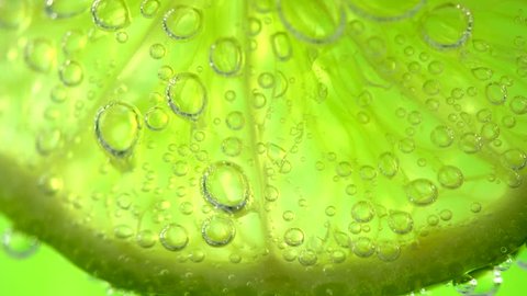 Close-up of a delicious ripe Lime with bubbles. Mojito cocktail closeup. Healthy food, cooking ingredient. Slices of juicy lemon. Food background, backdrop 4K UHD video