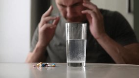man taking pills at lifestyle home is ill sick slow motion video. Healthcare and medical concept disease. male takes a pill and drinks a glass of water indoors
