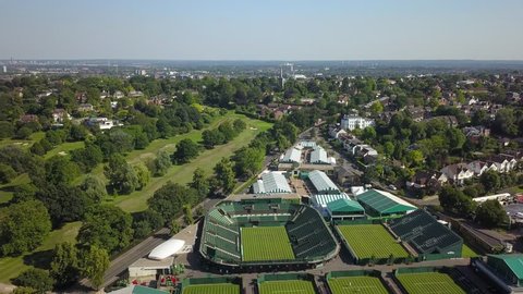 Aerial drone footage of the tennis stadium complex in Wimbledon, London, England on a bright sunny day.