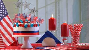 Happy Independence Day 4th of July with cake, flags and party hats in red white and blue theme.