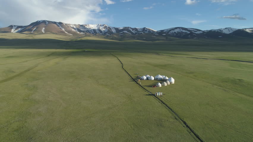 Yurts in Valley and Mountains on Background in Sunny Summer Day. Aerial View. Drone is Orbiting Around