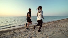 Side view of Attractive sports couple running and having fun together on beach near the sea