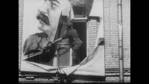 1930s: Man tears down poster of Stalin. Men hammer statues of Stalin. Men topple statues of Stalin. Men hang poster of Hitler in window.