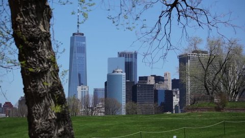 Lower Manhattan beyond Governors Island grass on a sunny day in New York City.