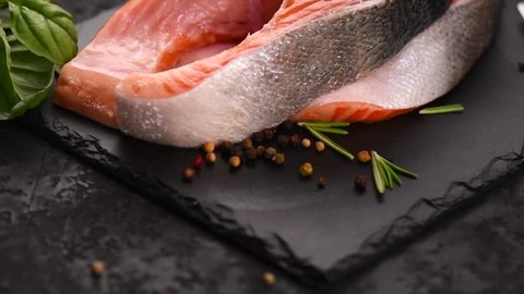 Salmon. Raw Trout Red Fish Steak with Herbs and Lemon and olive oil on slate. Cooking Salmon, sea food. Healthy eating concept. Slow motion 4K UHD video