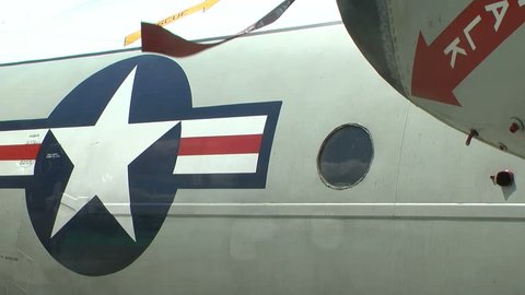 Fuselage side of a US military aircraft.  Roundel logo prominent.  Remove before flight flag banner ribbon blows in the breeze.