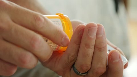 A dolly shot of a man getting ready to overdose on prescription drugs in his home