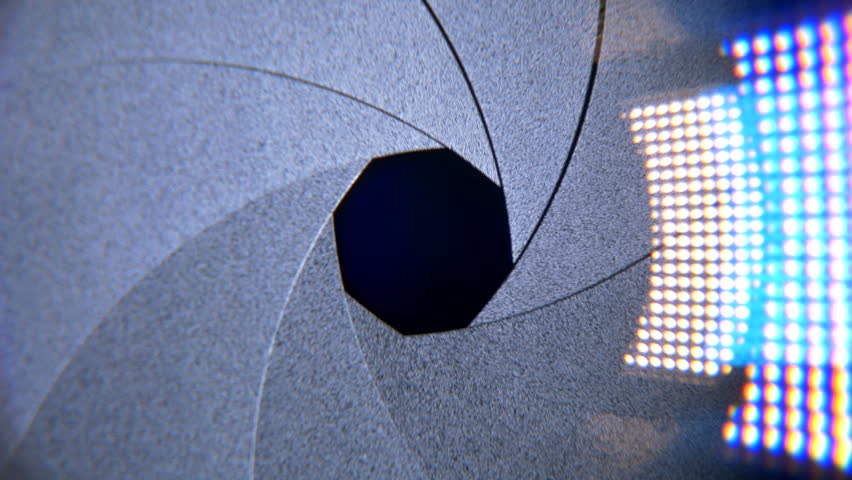 This Video shows a Zooming Close Up of a Camera Lens. Aperture of Camera Lens is slowly opening with Lens Flares. This looping Shot of a Recording Camera is perfect for Topics in Cinematography, Journ