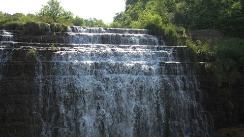 View of the beautiful Thunder Bay Waterfall with water pouring over the rocky stepped cliff located along a road in Galena Illinois.