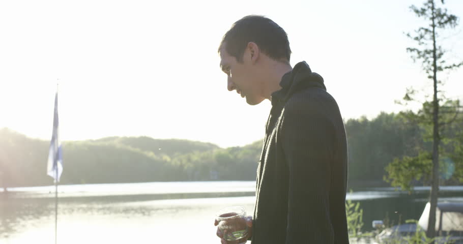 Young 20s man enjoying alcholic drink at cottage - finishes off drink